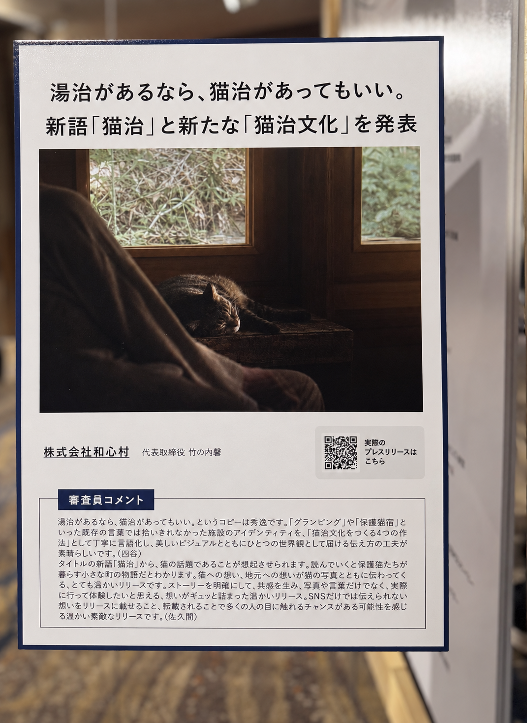猫治文化を紹介する和心村の展示パネル。タイトル、猫が窓辺で休むビジュアル、QRコード、審査員コメントを掲載
